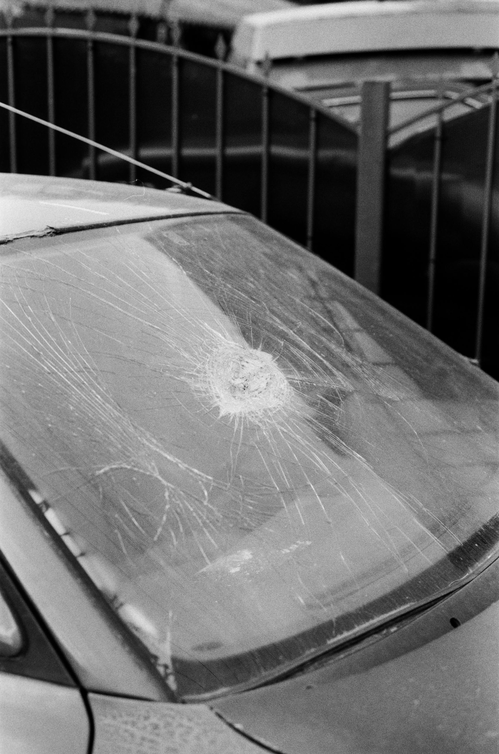 Une image en noir et blanc d'une voiture avec un pare-brise brisé, mettant en avant les dommages et la texture.