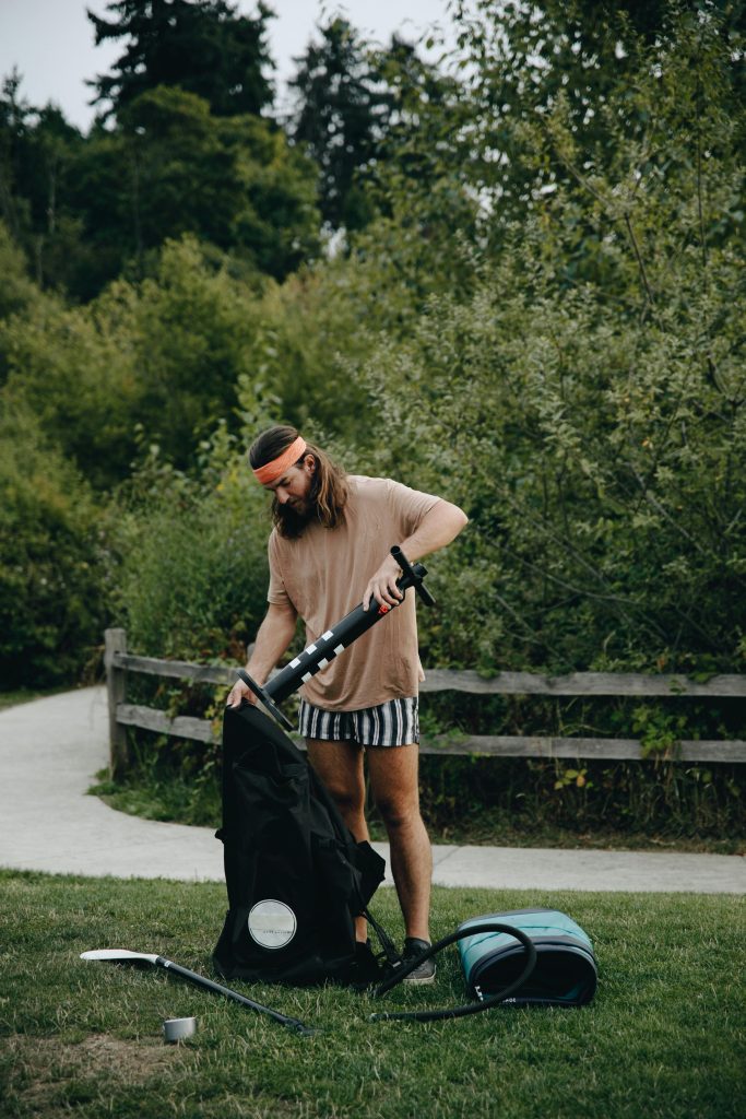 Un homme gonfle un matelas pneumatique dans un parc pittoresque, idéal pour le camping et les activités de plein air.