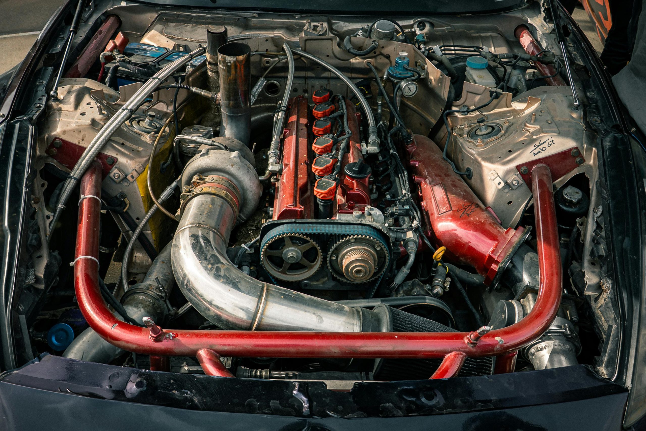Détail d'un moteur de voiture modifié avec des accents rouges, mettant en valeur ses composants.