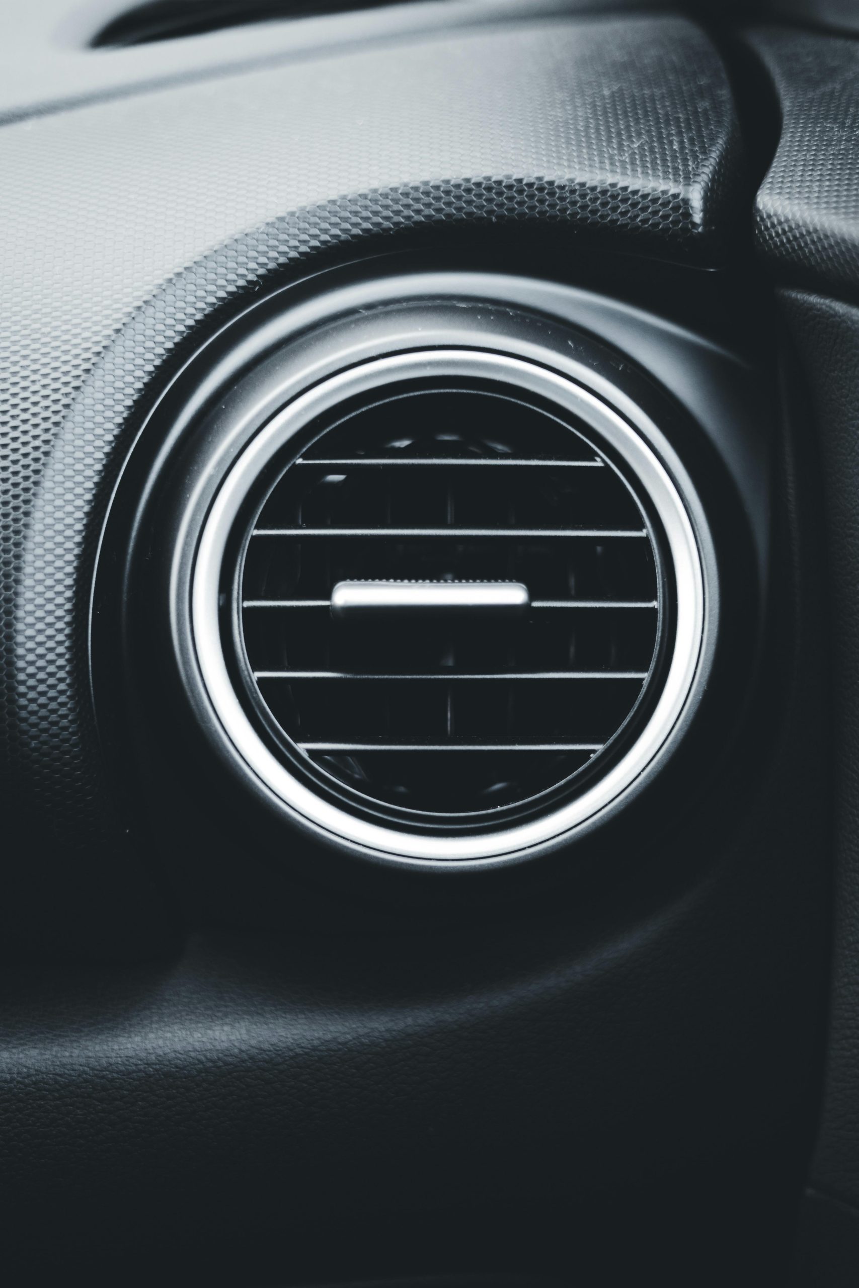 Détail rapproché d'une bouche d'aération de voiture mettant en valeur le design intérieur moderne d'un véhicule.