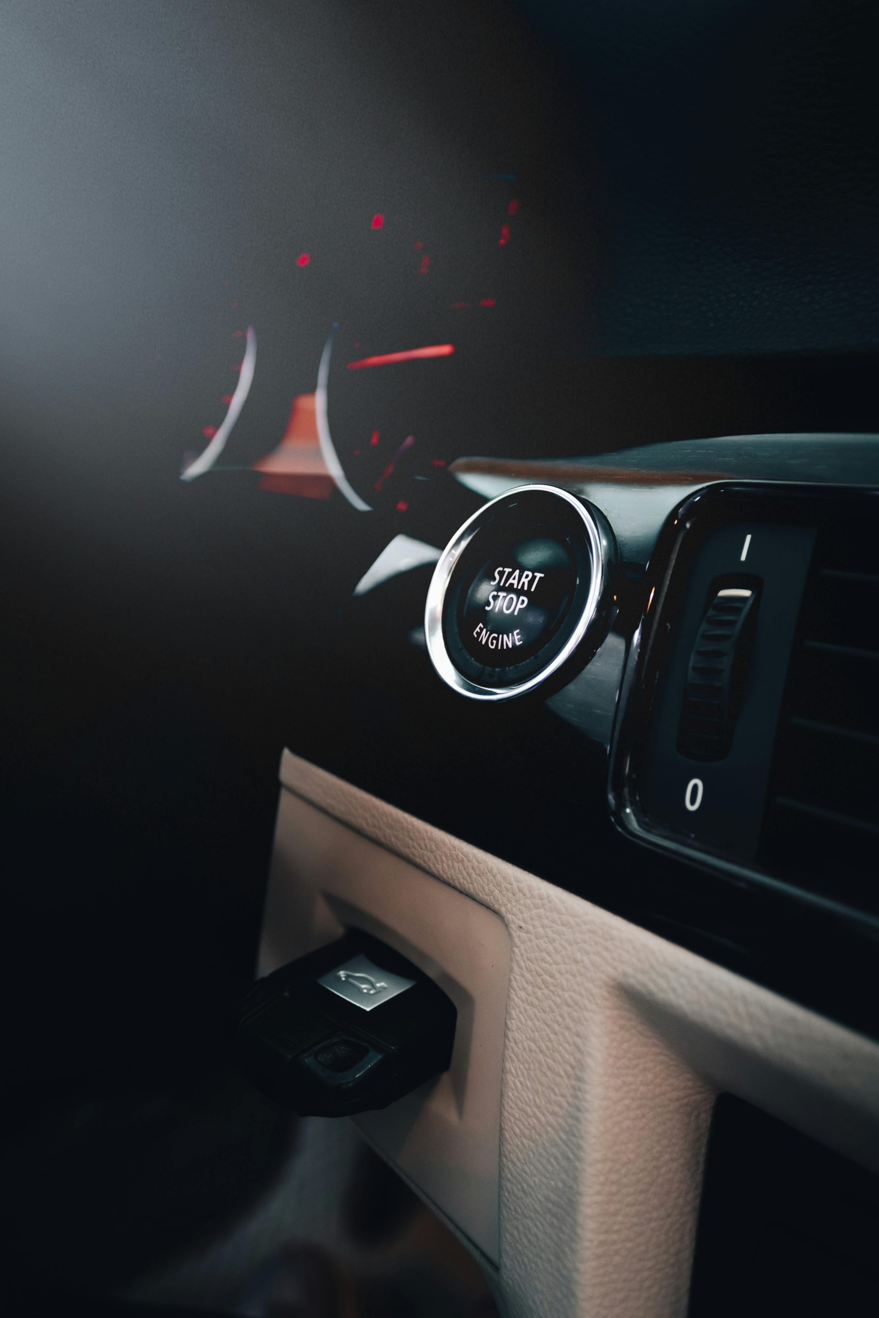 Close-up du tableau de bord d'une voiture mettant en avant un bouton start-stop illuminé.