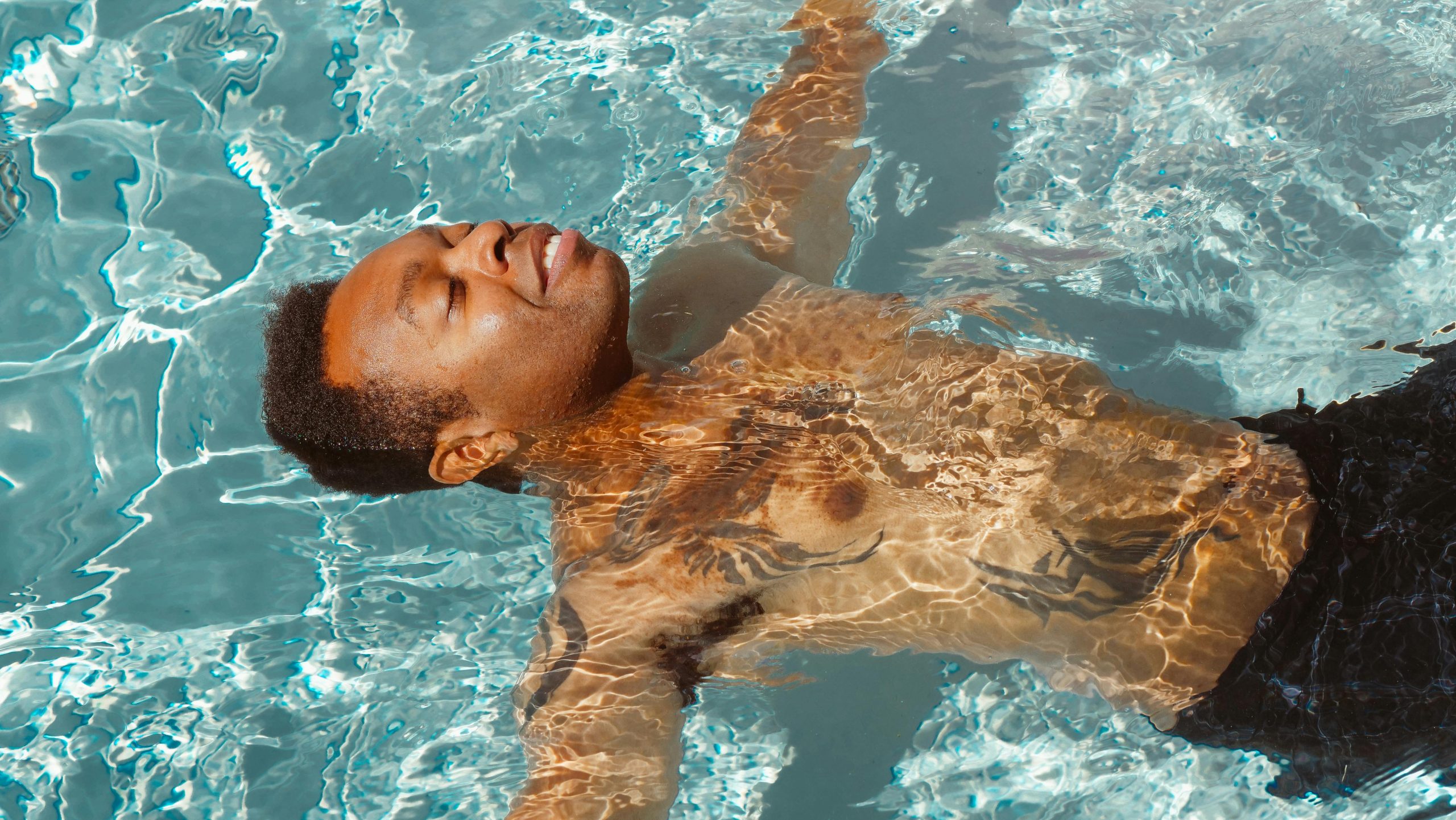 Un homme flotte paisiblement dans une piscine ensoleillée, profitant d'une journée d'été relaxante.