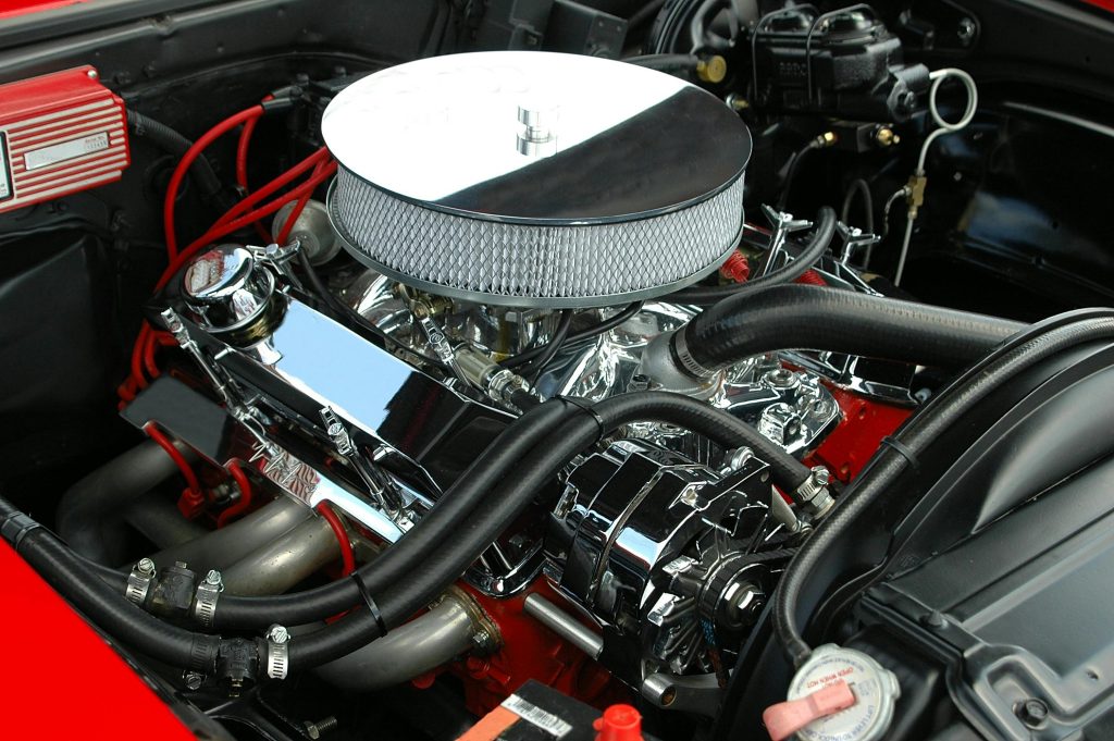 Detailed view of a polished, high-performance car engine showcasing chrome detailing and intricate mechanics. Vue détaillée d'un moteur de voiture haute performance poli mettant en évidence les détails chromés et la mécanique complexe.