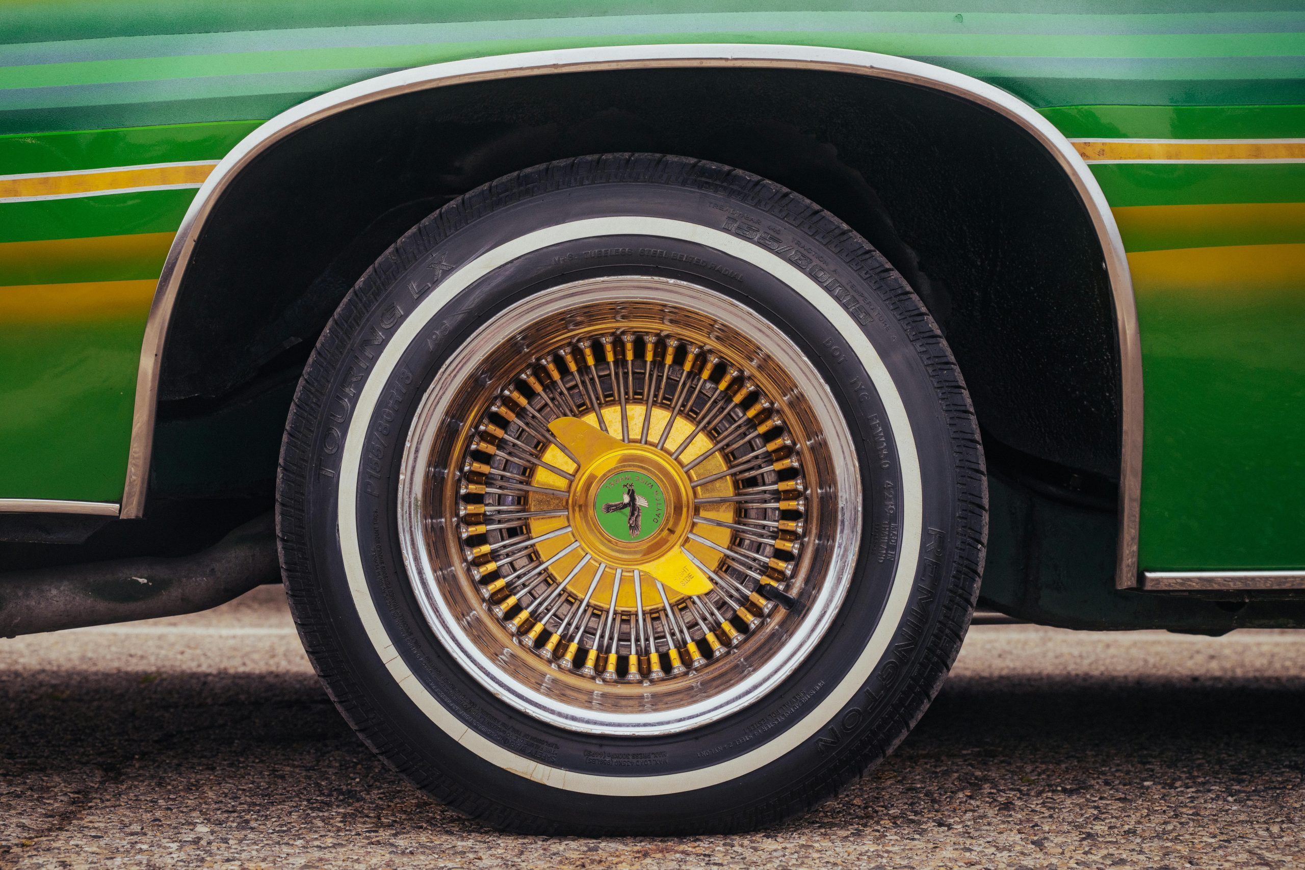 Détail d'une roue de voiture vintage aux couleurs vives vert et jaune.