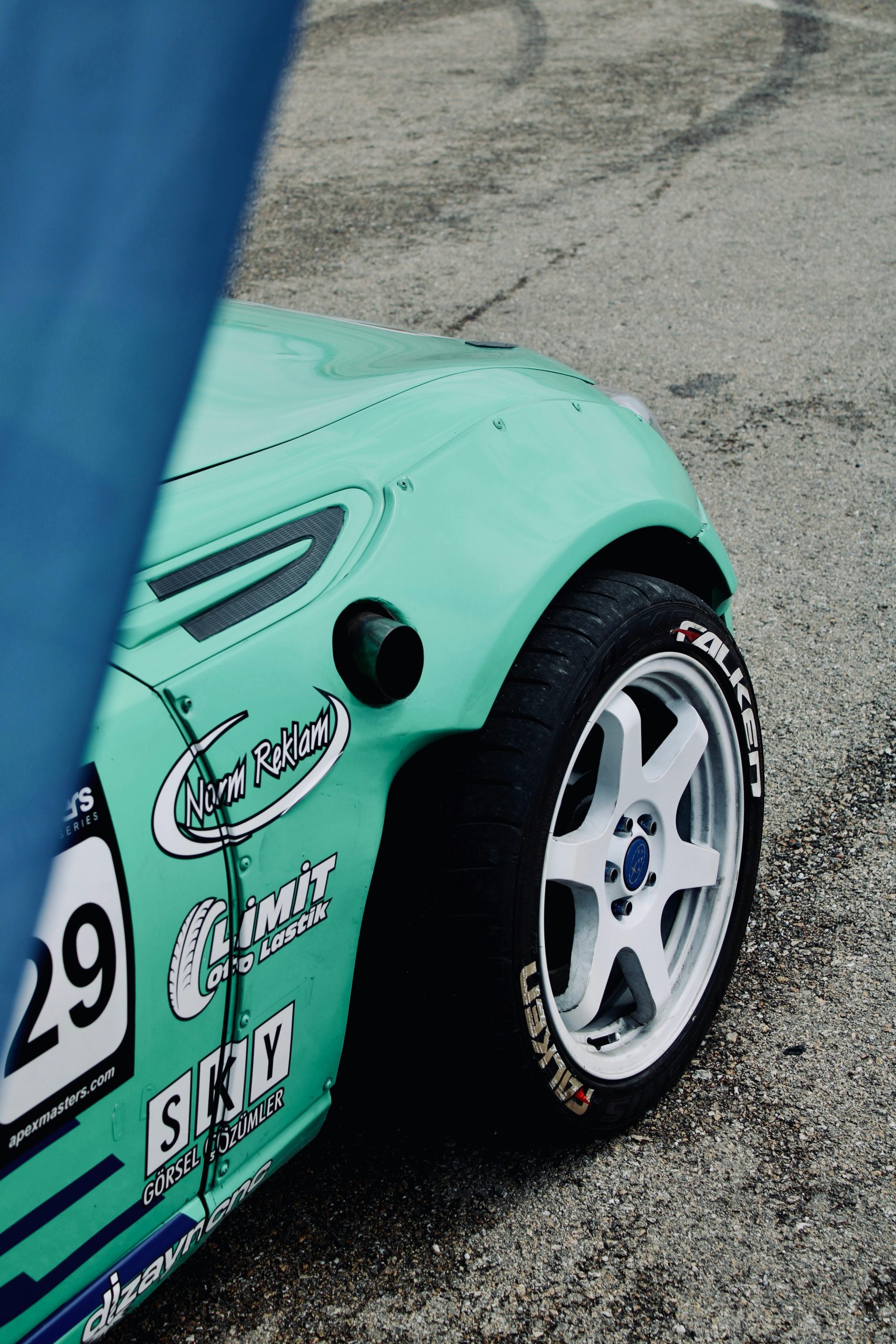A vibrant green racing car's wheel close-up on a track in Turkey. La roue en gros plan d'une voiture de course verte éclatante sur une piste en Turquie.