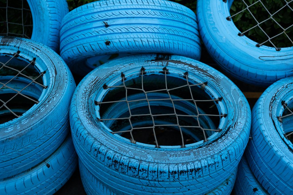 Bright blue painted tires stacked with a creative lattice pattern, showcasing recycling art. Des pneus peints bleu vif empilés selon un motif de treillis créatif, mettant en valeur l'art du recyclage.
