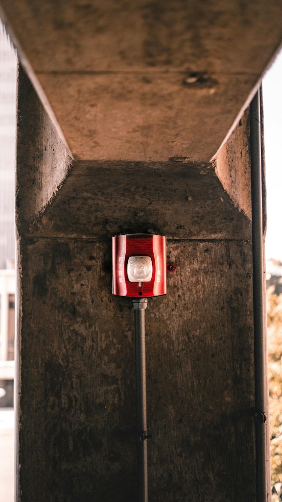 Red fire alarm switch system attached to stone wall of aged building on city street Système d'interrupteur d'alarme incendie rouge fixé au mur en pierre d'un bâtiment ancien dans la rue de la ville