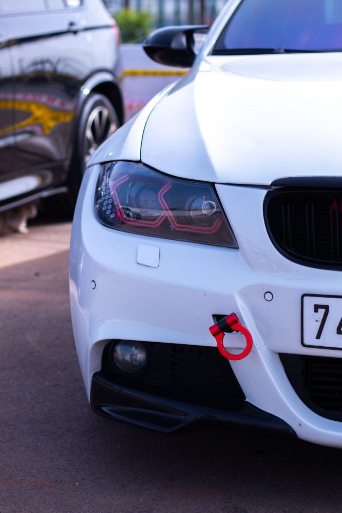 Detailed view of a white car's front headlight and bumper in daylight, ideal for automotive themes. Vue détaillée du phare avant et du pare-chocs d'une voiture blanche à la lumière du jour, idéale pour les thèmes automobiles.