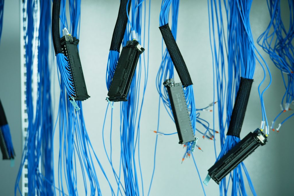 Close-up of blue ethernet cables hanging in a data center, highlighting technology connections. Gros plan sur des câbles Ethernet bleus suspendus dans un centre de données, mettant en évidence les connexions technologiques.