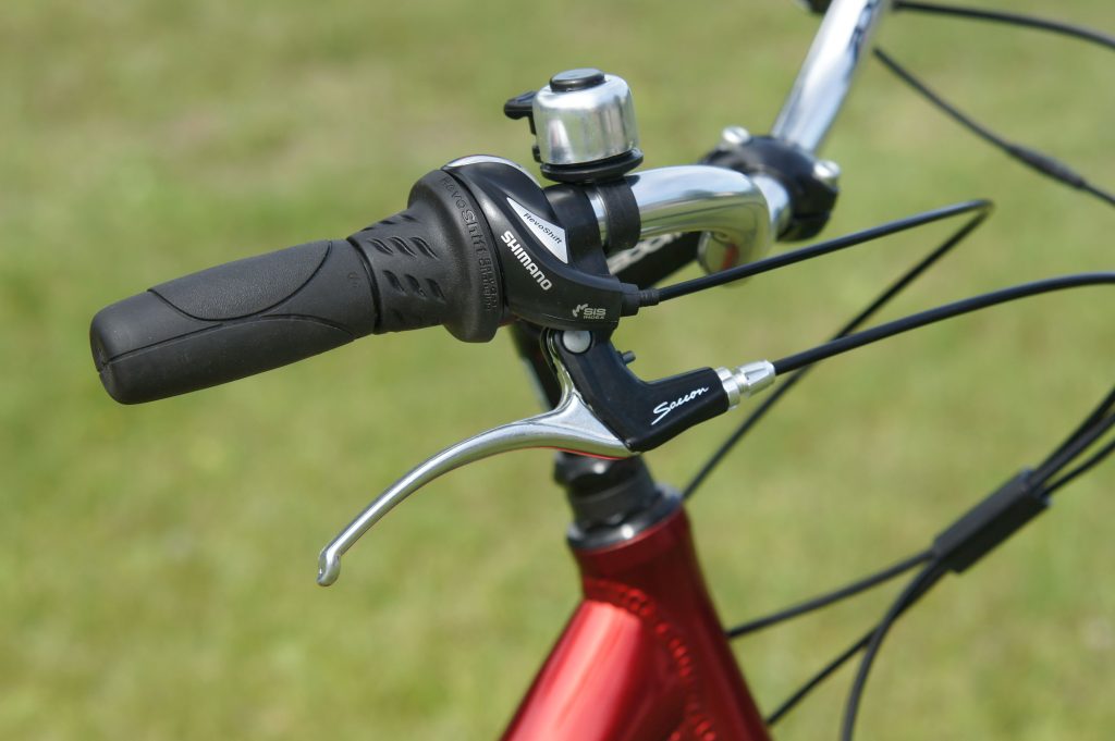 Detailed view of a bicycle's handlebar, brake lever, and bell. Vue détaillée du guidon d'un vélo, du levier de frein et de la sonnette.