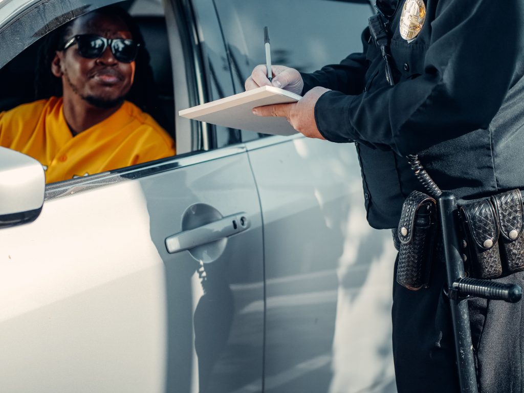 A police officer writes a ticket for a driver in a car during a roadside stop. Un policier rédige un PV pour un conducteur dans une voiture lors d'un contrôle routier.