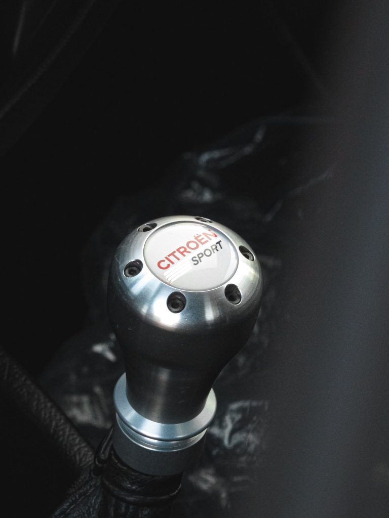 Detailed view of a Citroën Sport gear shift knob inside a vehicle. Vue détaillée du bouton de levier de vitesse Citroën Sport à l'intérieur d'un véhicule.
