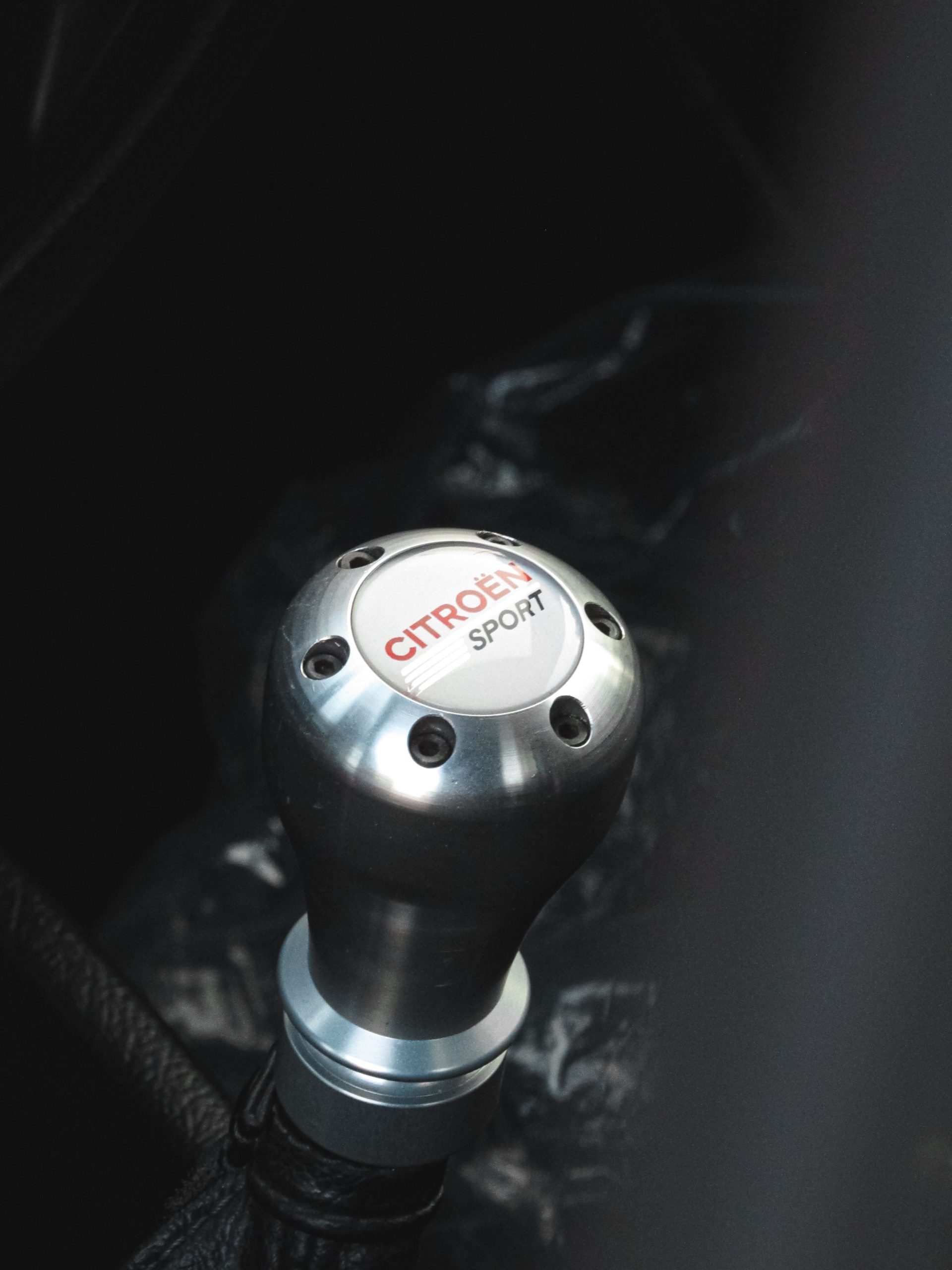 Detailed view of a Citroën Sport gear shift knob inside a vehicle. Vue détaillée du bouton de levier de vitesse Citroën Sport à l'intérieur d'un véhicule.
