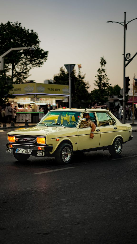 A retro car driving through city streets during sunset, capturing urban vibes. Une voiture rétro conduisant dans les rues de la ville au coucher du soleil, capturant les ambiances urbaines.