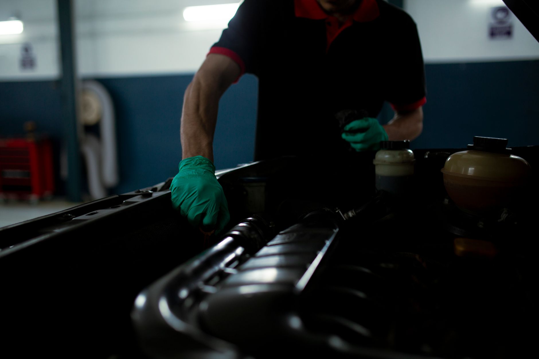 Main gantée qui contrôle le niveau d'huile moteur au garage