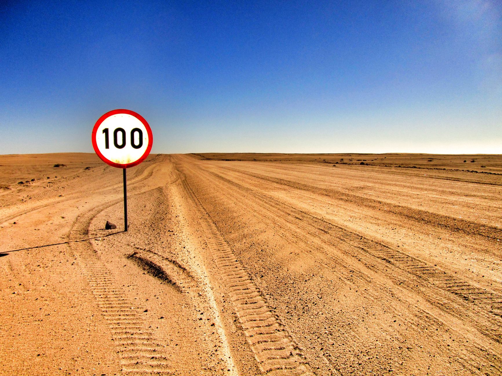 Panneau de limitation a 100 km/h sur route desertique