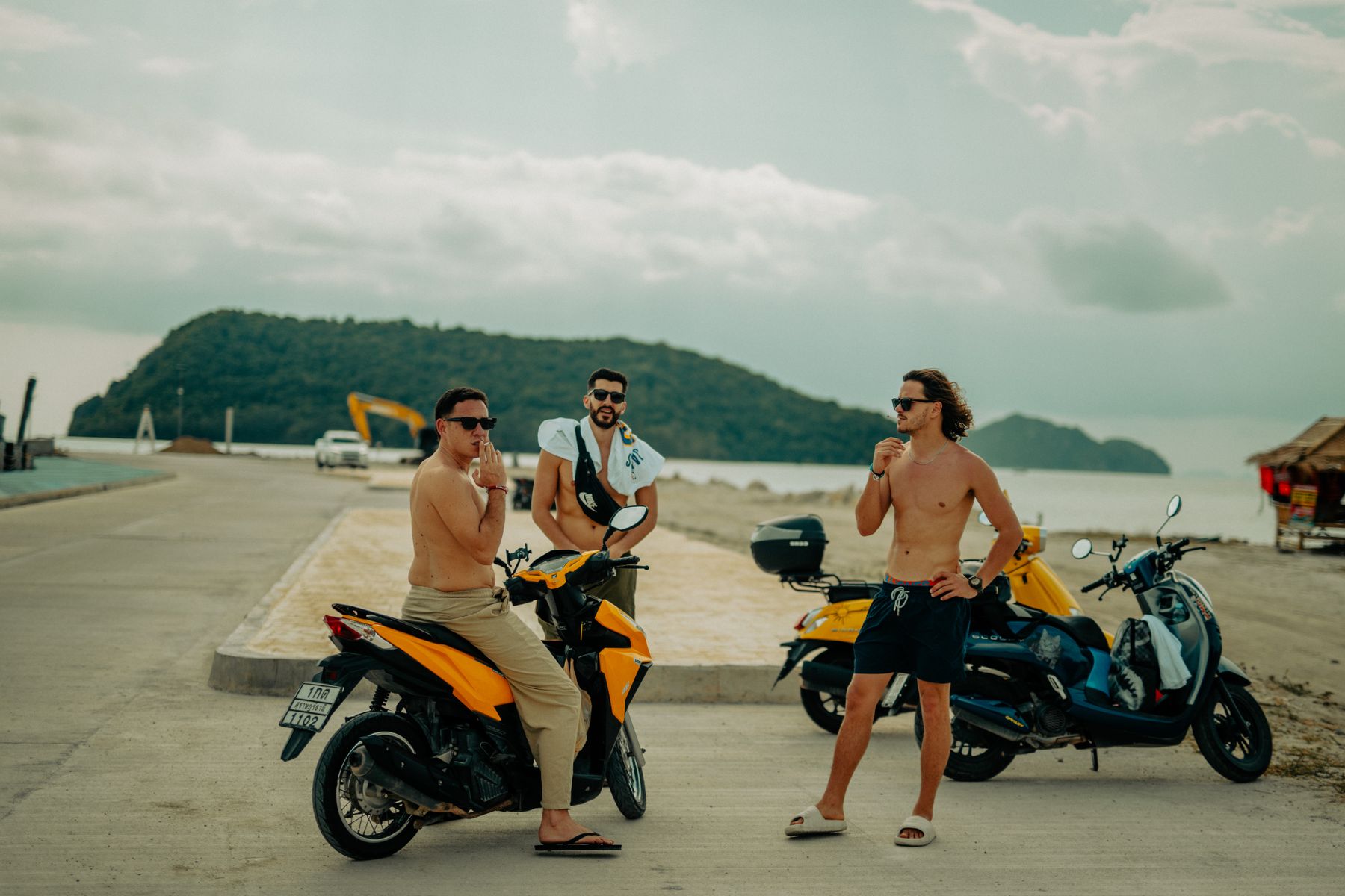 Amis souriants appuyés sur des scooters au bord de mer