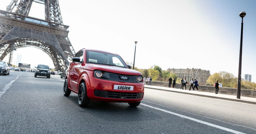 Voiture sans permis Ligier rouge roulant à Paris devant la tour Eiffel
